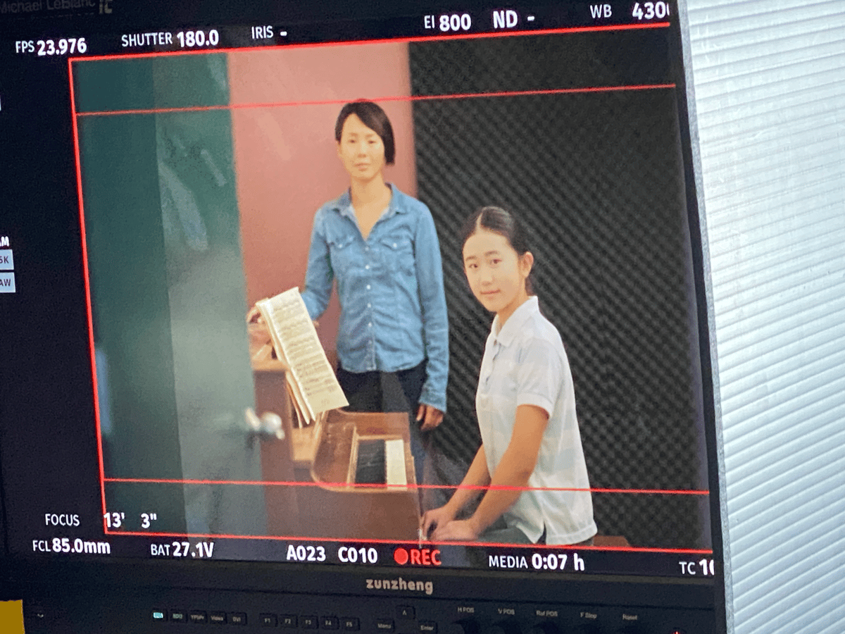 Sarah on a film set beside a piano